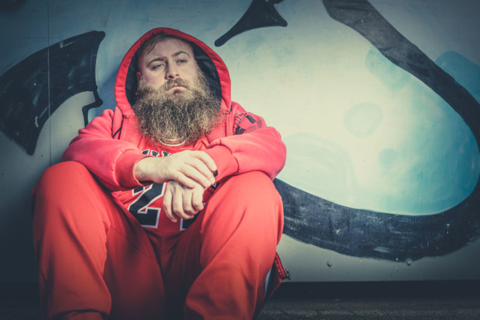 Bartmodel sitzend vor einer Graffiti Wand © Copyright UK Photographie