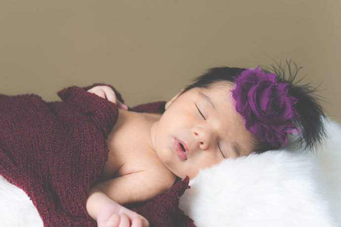 Zusehen ist ein Baby liegen mit roten Tuch gewickelt © Copyright UK Photographie